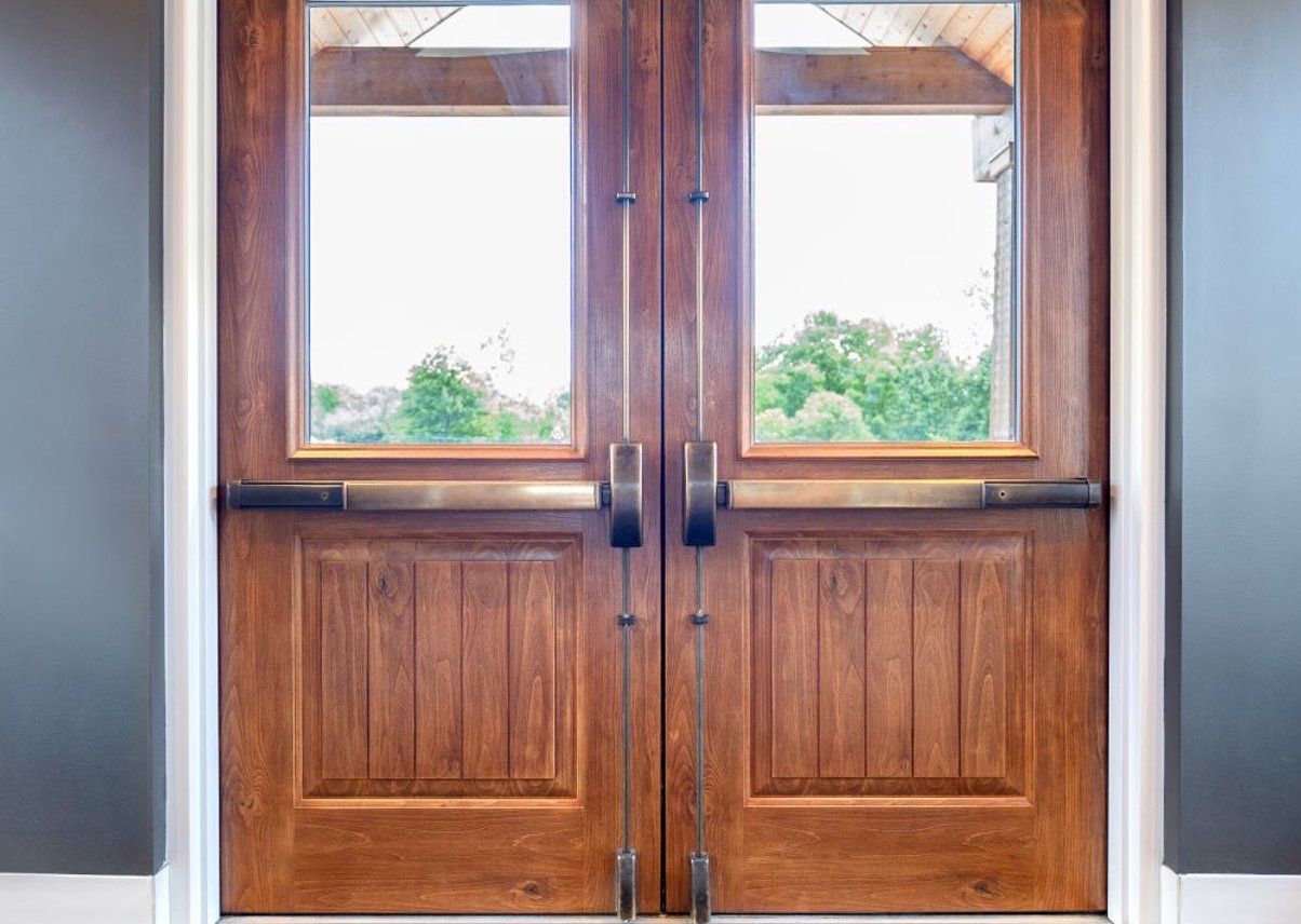 White house exterior with double wood doors and American flag.